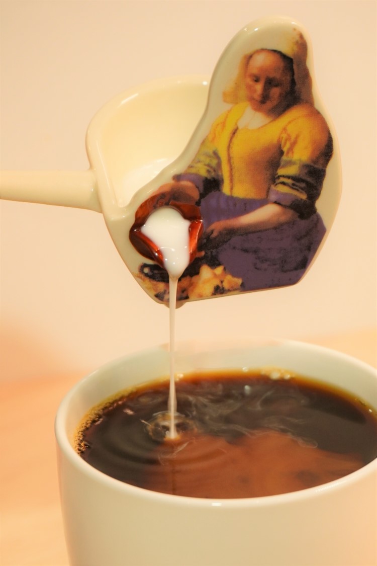 コーヒーに牛乳を注ぐ女